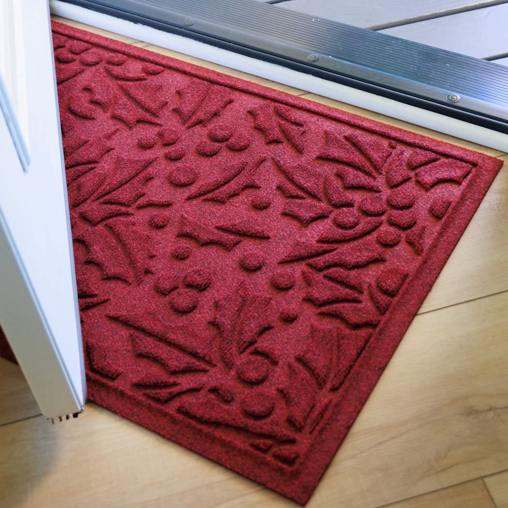 Rich red indoor/outdoor doormat with holiday floral pattern on a wooden floor