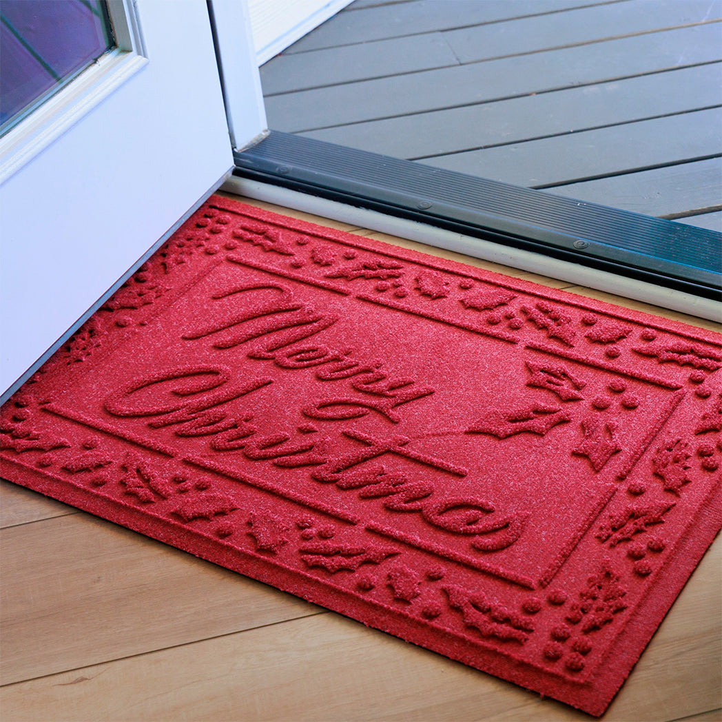Beautiful holiday red doormat with 'Merry Christmas' text on a wooden floor.