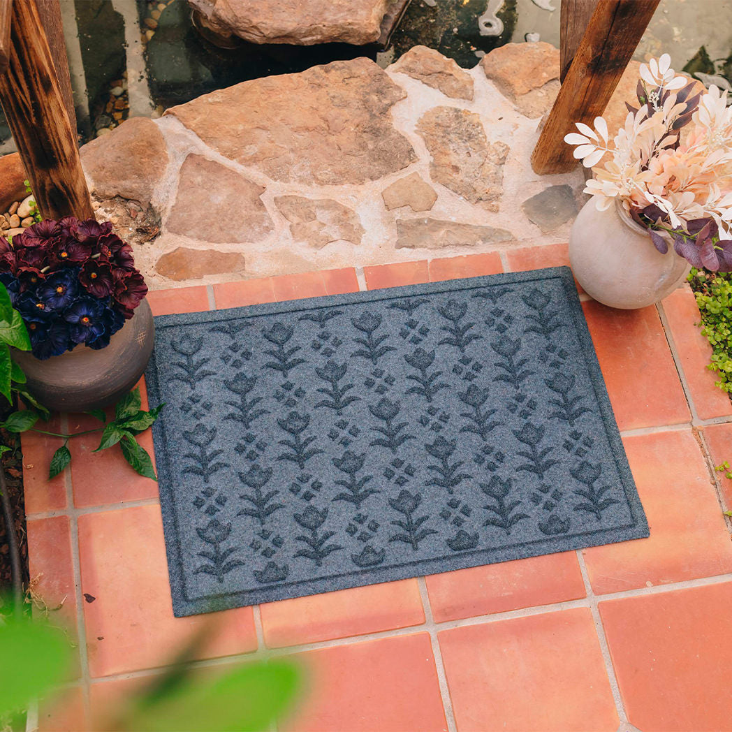 A fade resistant, blue colored doormat with a repeating floral design that's design for Anthropologie