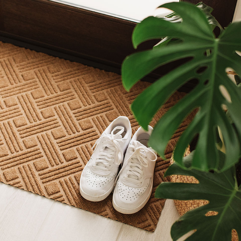 Matterly's WaterHog Luxe doormat in the Classic Thatch design with a pair of white tennis shoes resting on top