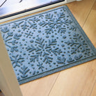 Blue with gray undertones doormat with snowflake pattern on a wooden floor
