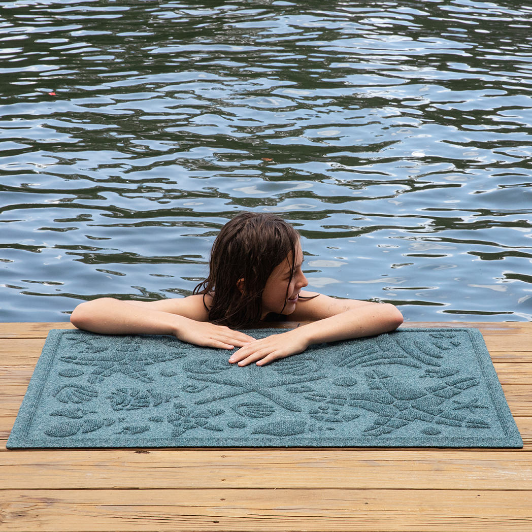 Blue beachcomber mat on a dock with a young girl resting on it