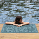 Blue beachcomber mat on a dock with a young girl resting on it
