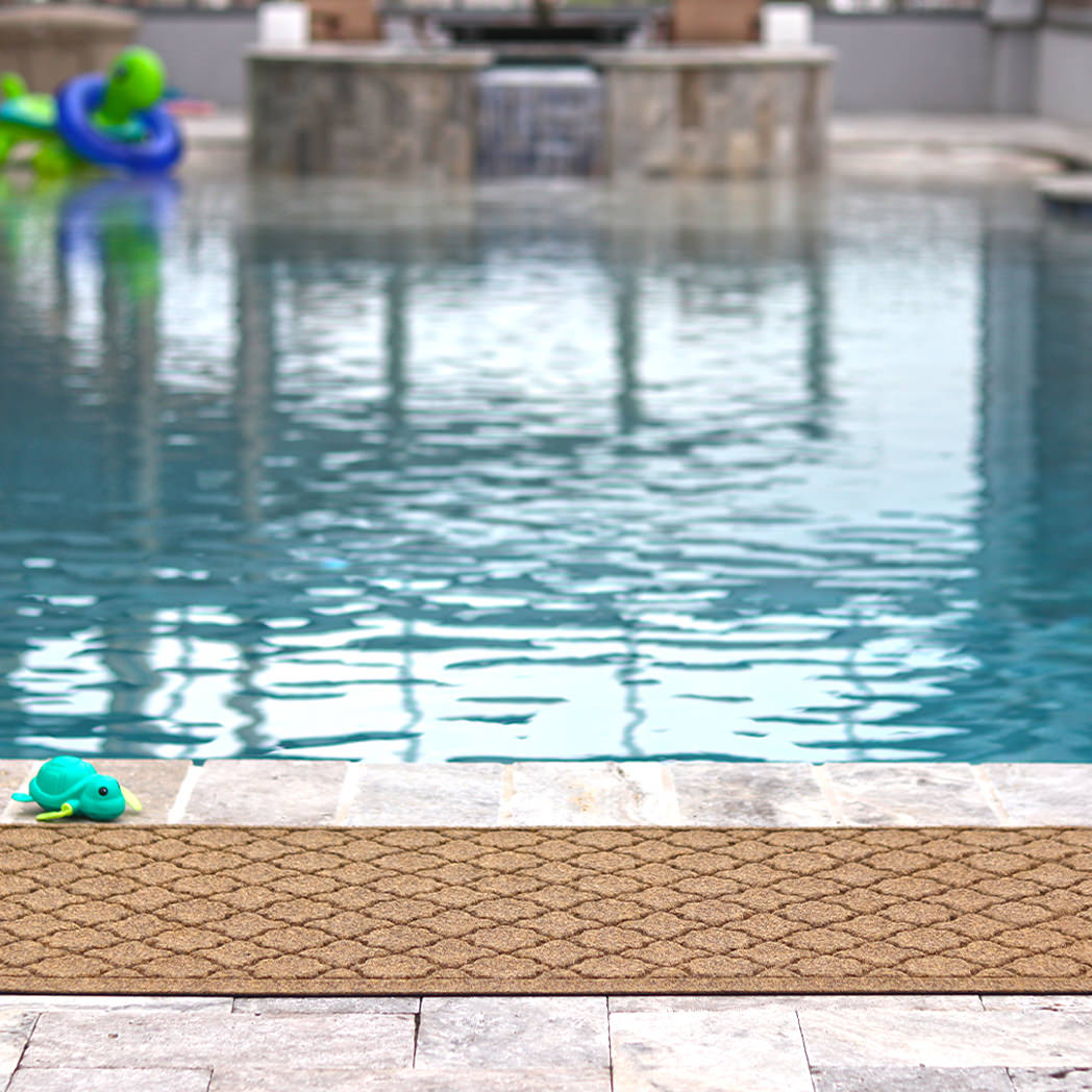 WaterHog Cordova waterproof outdoor runner mat placed next to a pool to help provide grip on slippery decks and other wet areas.