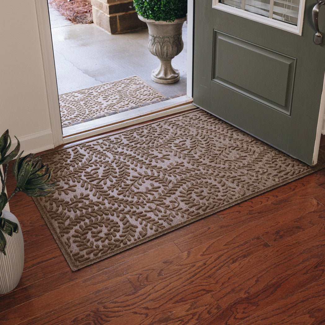 Large WaterHog Boxwood Indoor/Outdoor Doormat in light brown camel color placed just inside a front door on real wood floors to protect against damage causing moisture, dirt, sand, and debris.