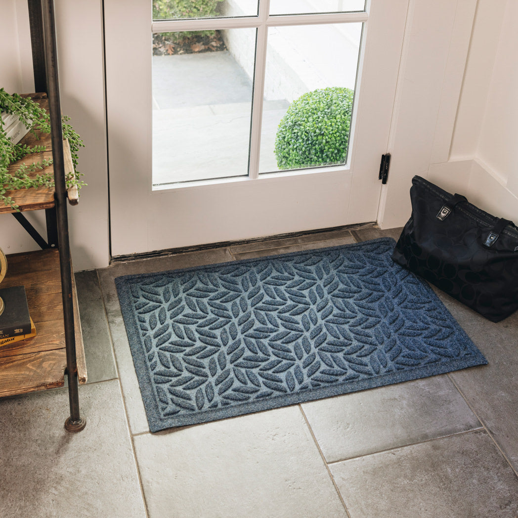 Genuine deep blue WaterHog indoor/outdoor doormat placed inside a home at a front or side door with a bag/purse placed beside it.