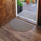 A durable, half-round doormat in a light tan color with a diamond pattern is placed inside a single door on wood flooring, while a large doormat of the same color and pattern is placed right outside the same single door.
