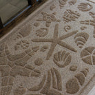 Close up on the bi-level seashell design on a camel Beachcomber mat at a front door