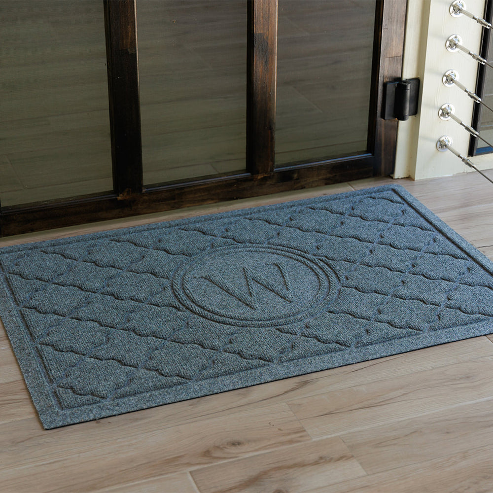 Blue monogramed Bombay doormat with the letter M at a wooden door