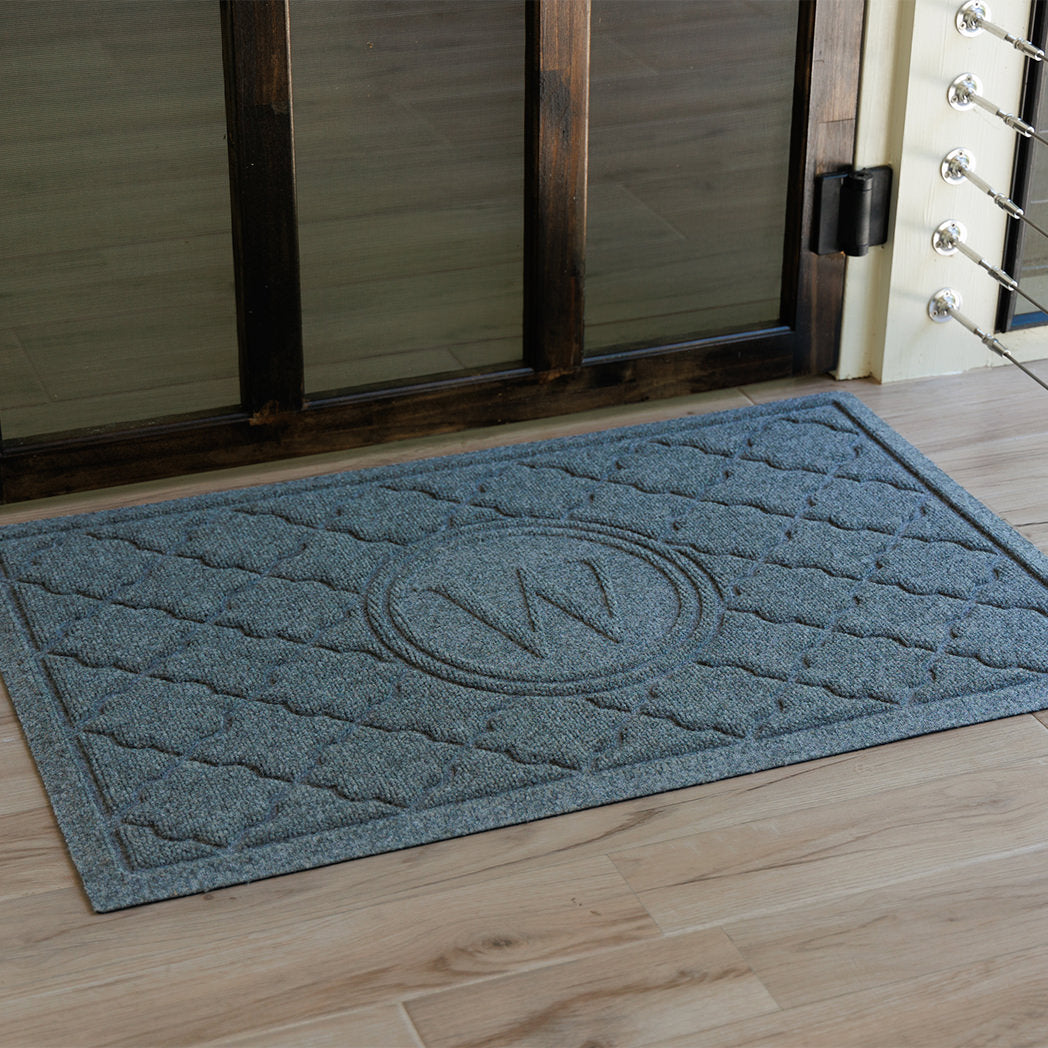 Blue monogramed Bombay doormat with the letter M at a wooden door
