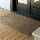 Decorative and protective WaterHog doormat with a leaf pattern on a wooden deck