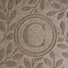Close up of the bi-level monogrammed 'C' on a WaterHog Brittney Leaf light sand doormat
