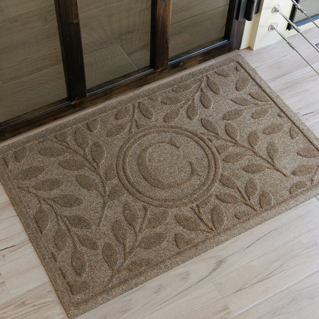 Monogrammed 'C' on a WaterHog Brittney Leaf doormat on a light wood floor