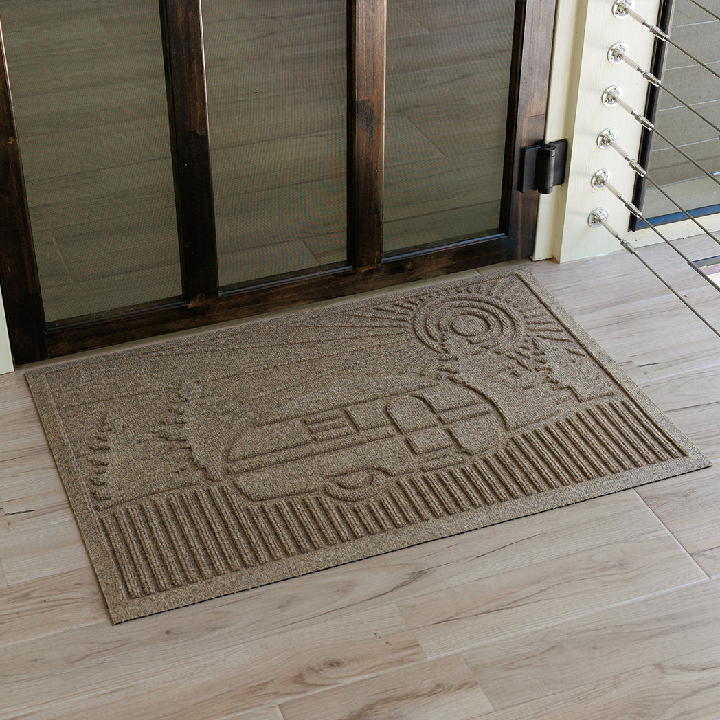 WaterHog doormat with a camper woodland design in front of glass door