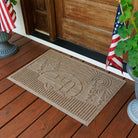 Doormat with a camper design on a wooden deck with American flags and plants.