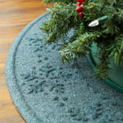 Light blue, bi-level snowflake design on an easy-to-clean tree skirt with a small Christmas tree on a wooden surface