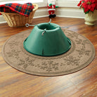 Green Christmas tree stand on a tan WaterHog Holiday Tree Skirt with holiday decorations in the background.