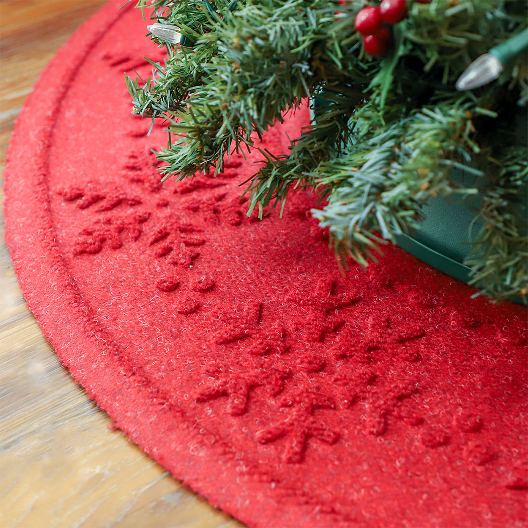 Bright red snowflake tree skirt mat covered in trapped pine needles from the tree