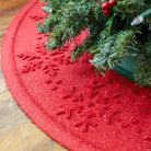 Bright red snowflake tree skirt mat covered in trapped pine needles from the tree