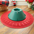 Green Christmas tree stand on a red WaterHog tree skirt mat with holiday decor in the background
