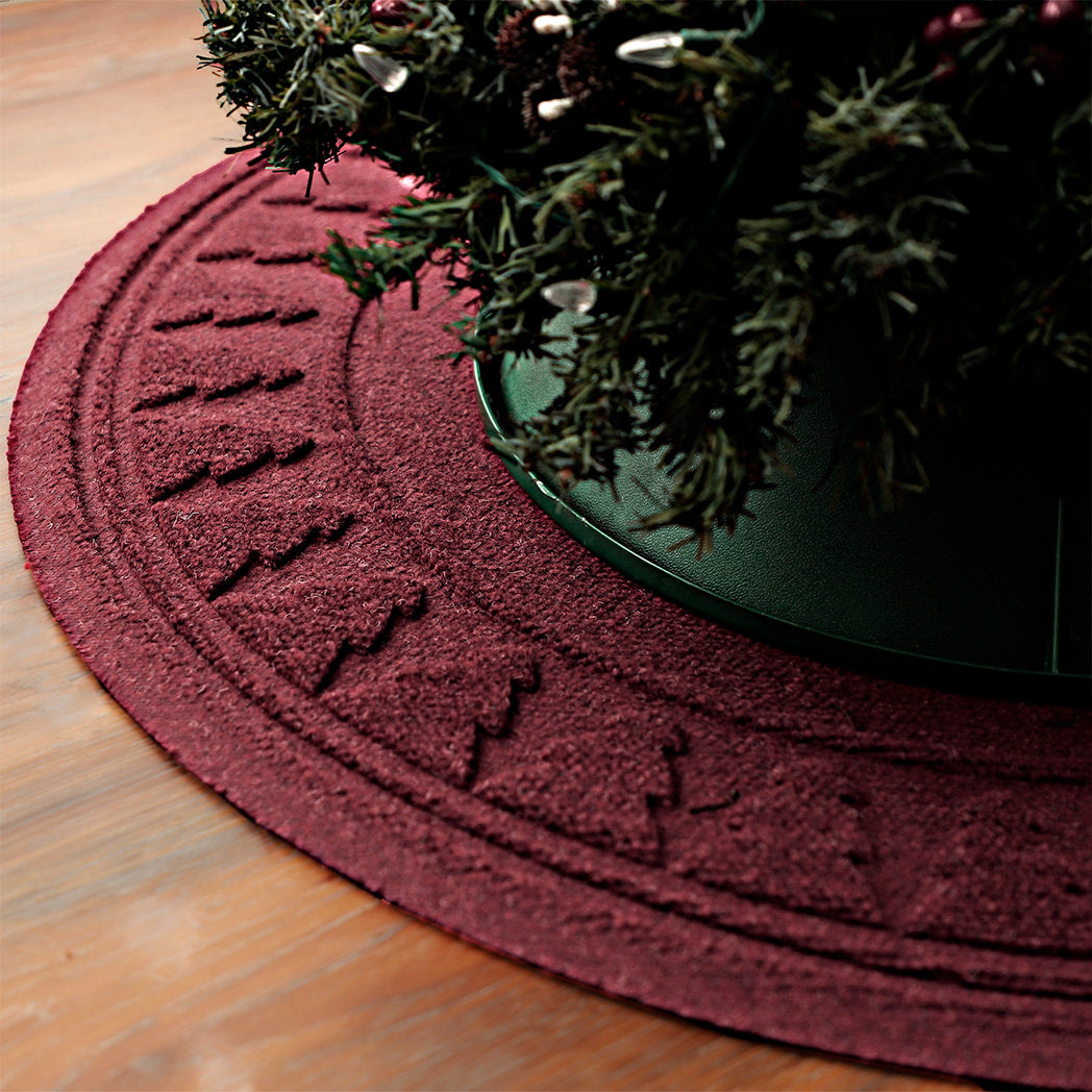 Close up a the edge of a WaterHog tree skirt in the color cranberry trapping pine needles from the tree