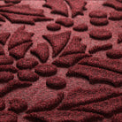 Close-up of a textured red holiday mat with holly pattern
