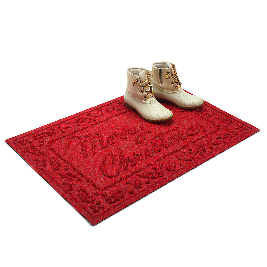 Bright red 'Merry Christmas' doormat shown at an angle with white boots on a white background