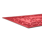 Red doormat with raised  'Merry Christmas' text and decorative border on a plain white background