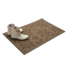 Tan doormat with snowflake pattern and white boots on a white background