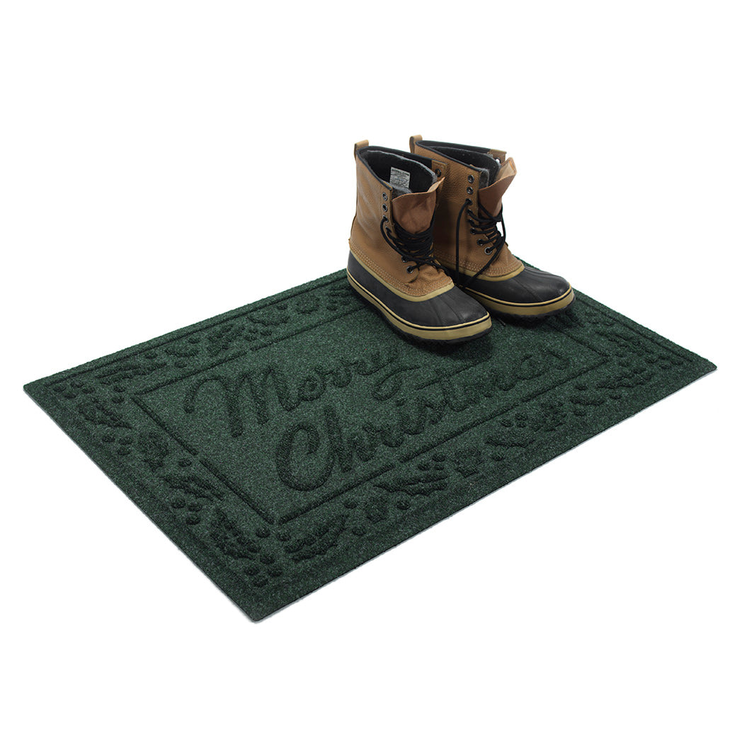 Deep green single-door doormat with 'Merry Christmas' text and a pair of men's boots on a white background