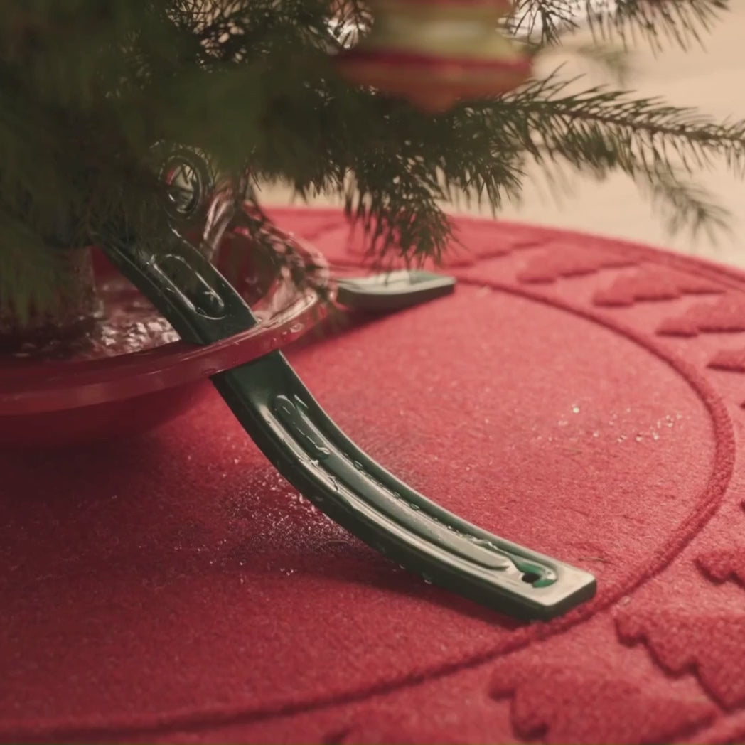 A floor protecting WaterHog Tree Skirt mat in bright red catching falling water and pine needles from a Christmas tree