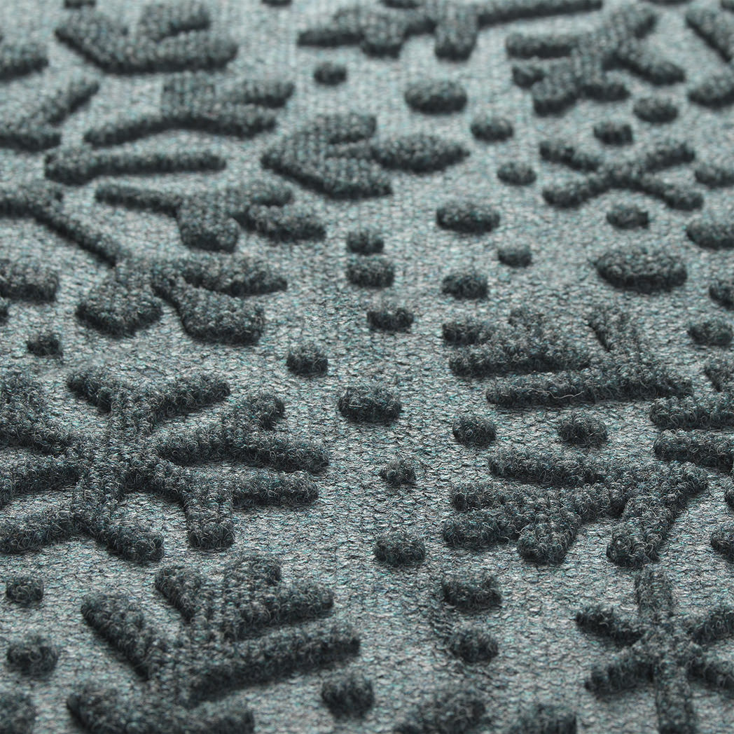 Close-up of a textured blue mat with a snowflake pattern consisting of PET fibers in blue, grey, while, and green