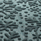 Close-up of a textured blue mat with a snowflake pattern consisting of PET fibers in blue, grey, while, and green