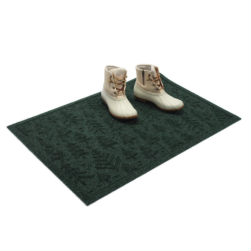 Two white boots on a green WaterHog doormat against a white background
