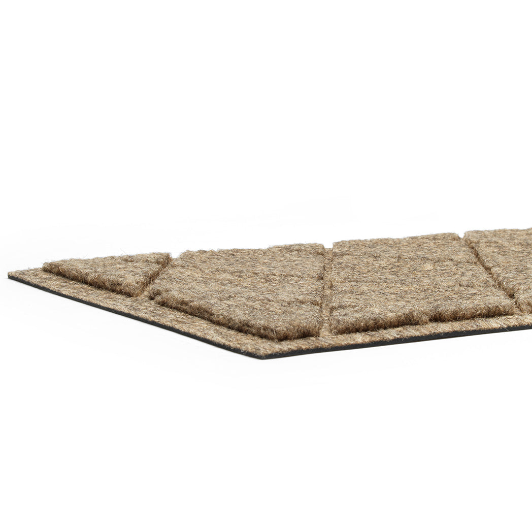 A close-up of WaterHog Argyle stair treads incredibly low height and durable rubber backing for better traction on the floor surface.