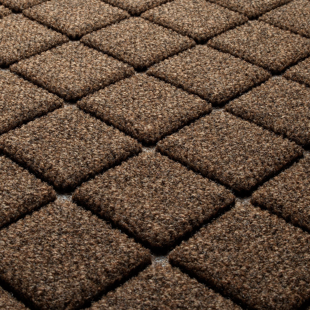 Detail shot of Argyle's surface made of light and dark brown, white, and black fibers, on a bi-level surface for scraping dirt and mud away.