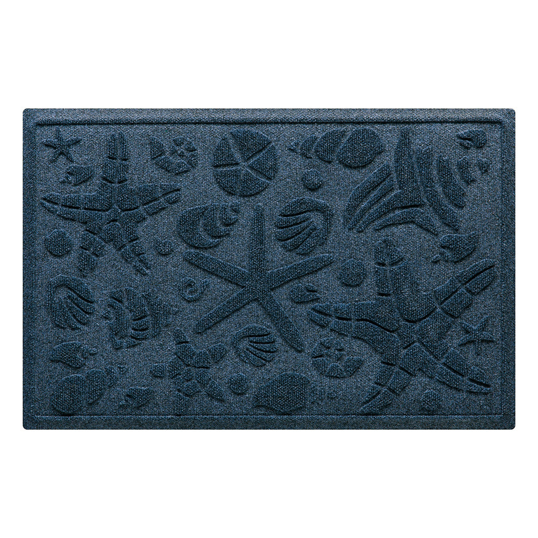 Isolated image of a nautical themed WaterHog Beachcomber medium size indoor/outdoor doormat that features a unique pattern of sea shells and starfish. Shown in navy color.