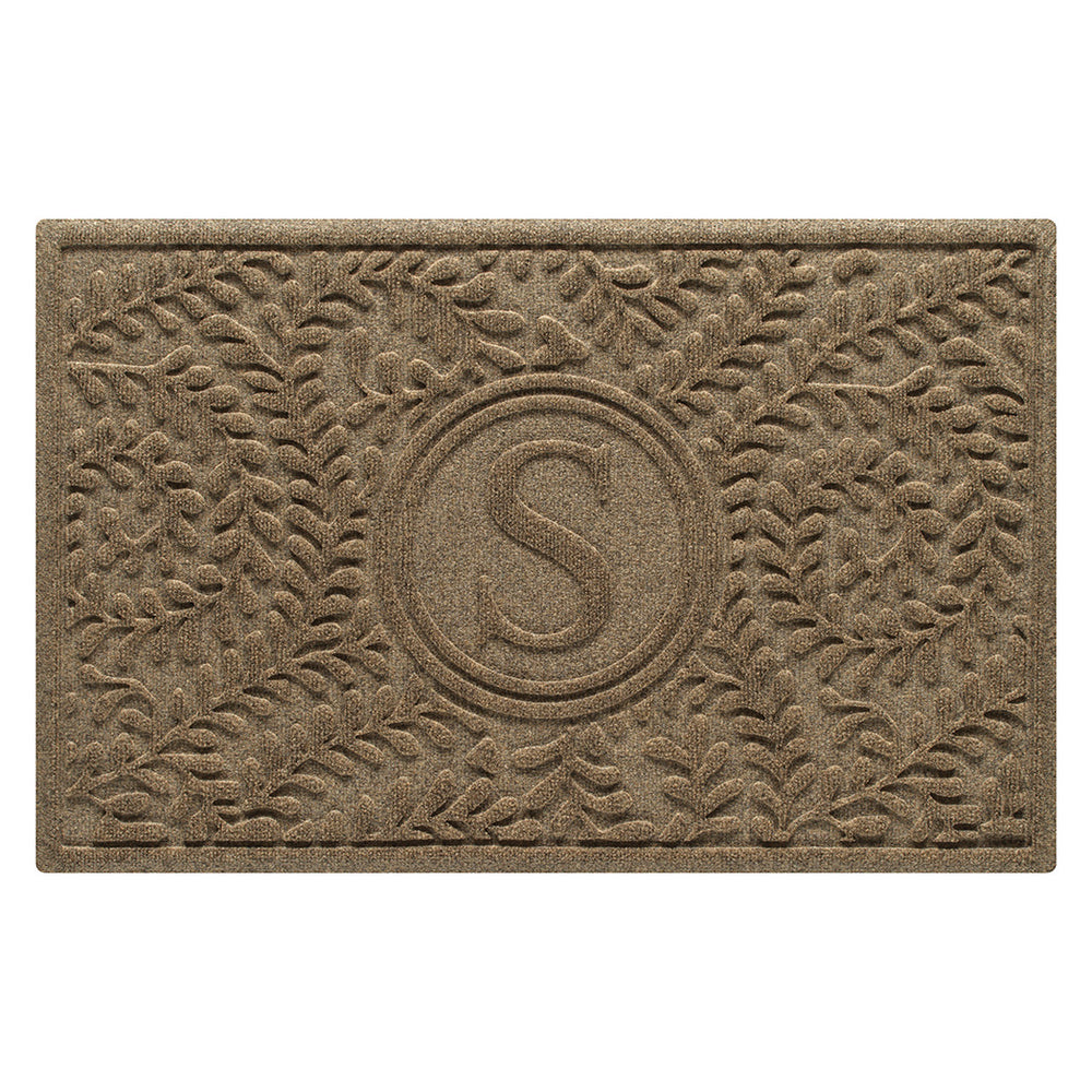 Overhead of a WaterHog Boxwood medium-sized monogram doormat in a light tan curling botanical, bi-level design.