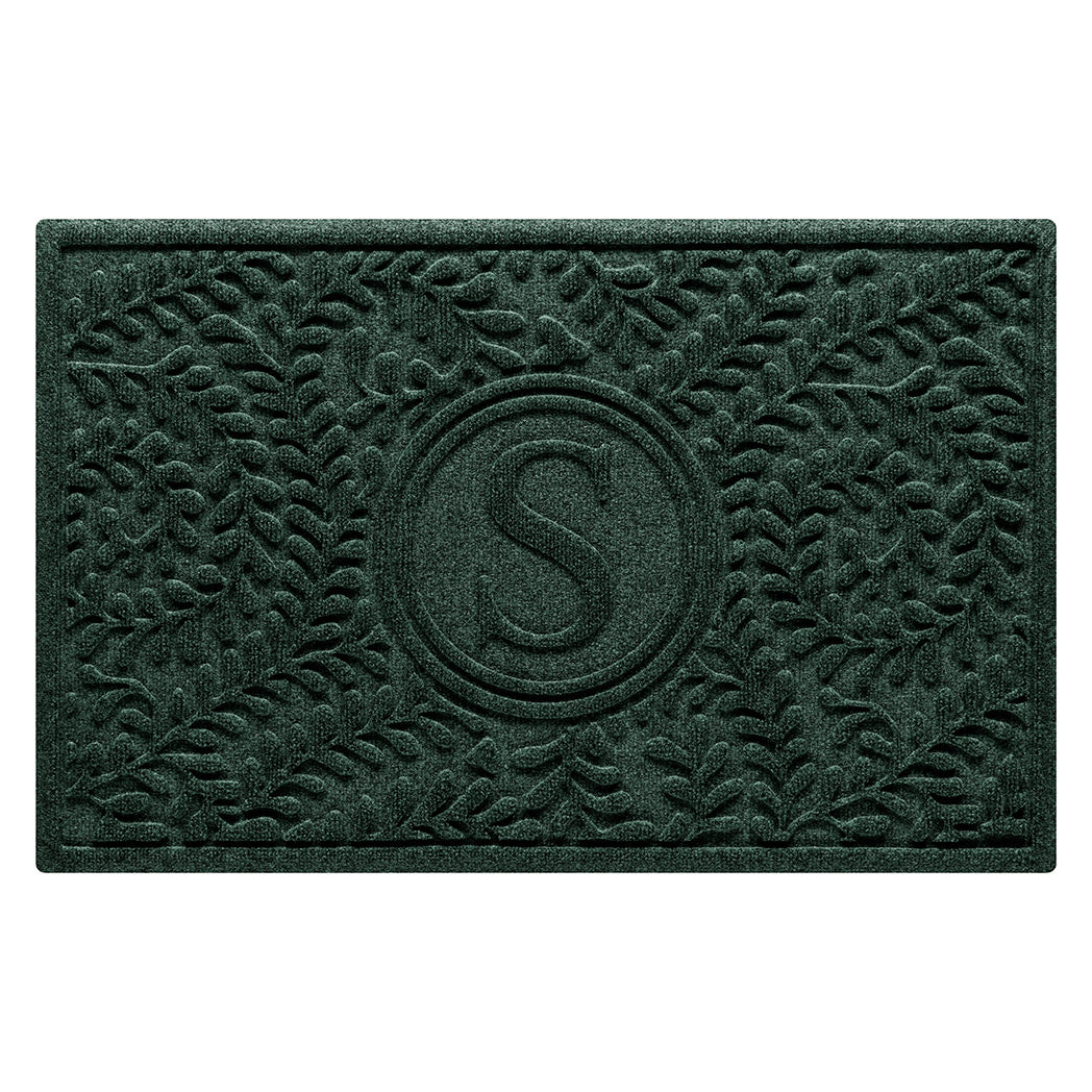 Overhead of a WaterHog 2x3 Boxwood monogram doormat with a deep green curling botanical pattern.