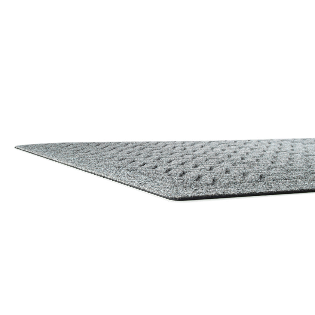 Side image of a very low-profile WaterHog mat in a medium-grey color with a textured fibrous surface and rubber packing to help prevent sliding.