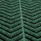 Close-up of a textured WaterHog doormat with a  chevron pattern made from a fibrous material consisting of colors green with some black and grey. The raised sections of the pattern create a three-dimensional effect designed for effective dirt and moisture trapping.