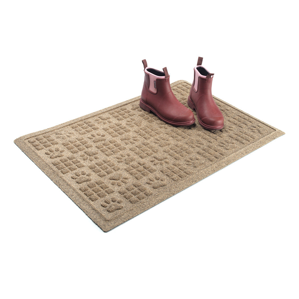 Bi-level 2x3 WaterHog doormat, with alternating squares and paw print pattern, in a light tan camel color with a pair of red and pink boots placed on top.