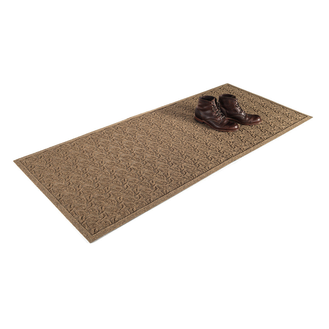 Isolated 2x5 Dogwood Leaf runner mat with a pair of brown leather boots on a white background