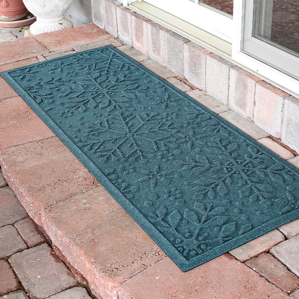 Blue textured doormat runner with snowflake pattern on a brick patio