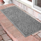 Gray doormat with a snowflake bi-level pattern on a brick patio