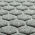 A close-up shot of the WaterHog Honeycomb all-weather doormat in light grey, displaying the carpeted fibers that form the raised design.