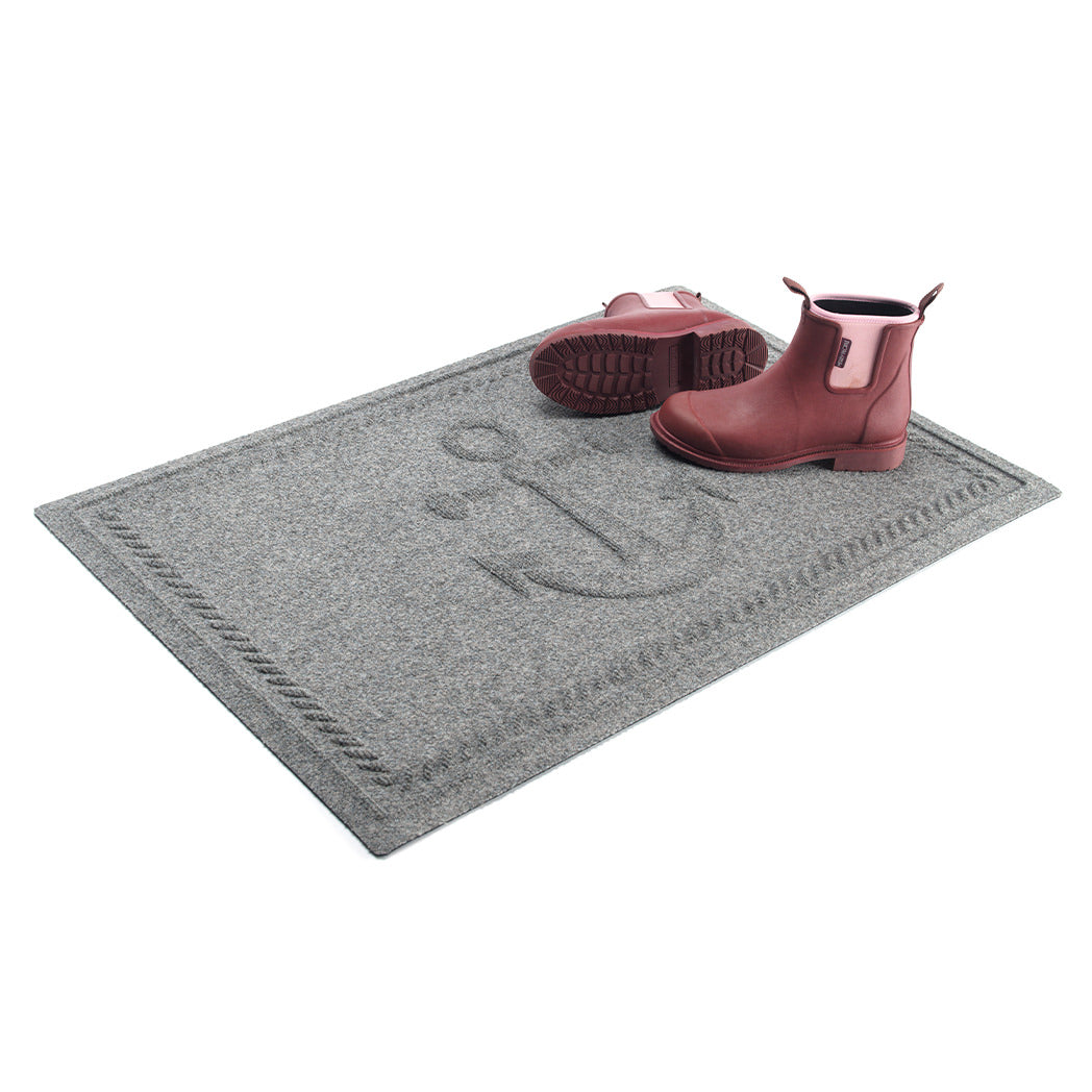 WaterHog Ship's Anchor all-weather doormat in light grey, featuring a raised anchor design in the center with a decorative rope like border, displayed on a white background with boots placed on top the mat.