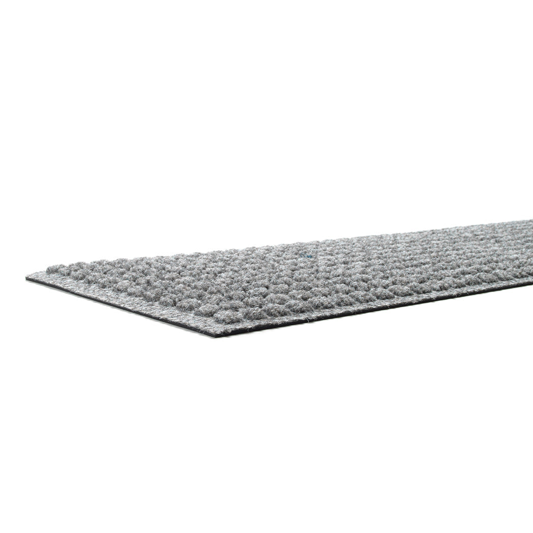 Close up shot of medium grey stair tread with a repeating squares pattern showing its low-profile height and incredibly durable rubber backing.