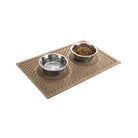 Angled Waves bowl mat in a light-brown tan camel color with small silver pet dishes resting in the circular set place, all on a white background.