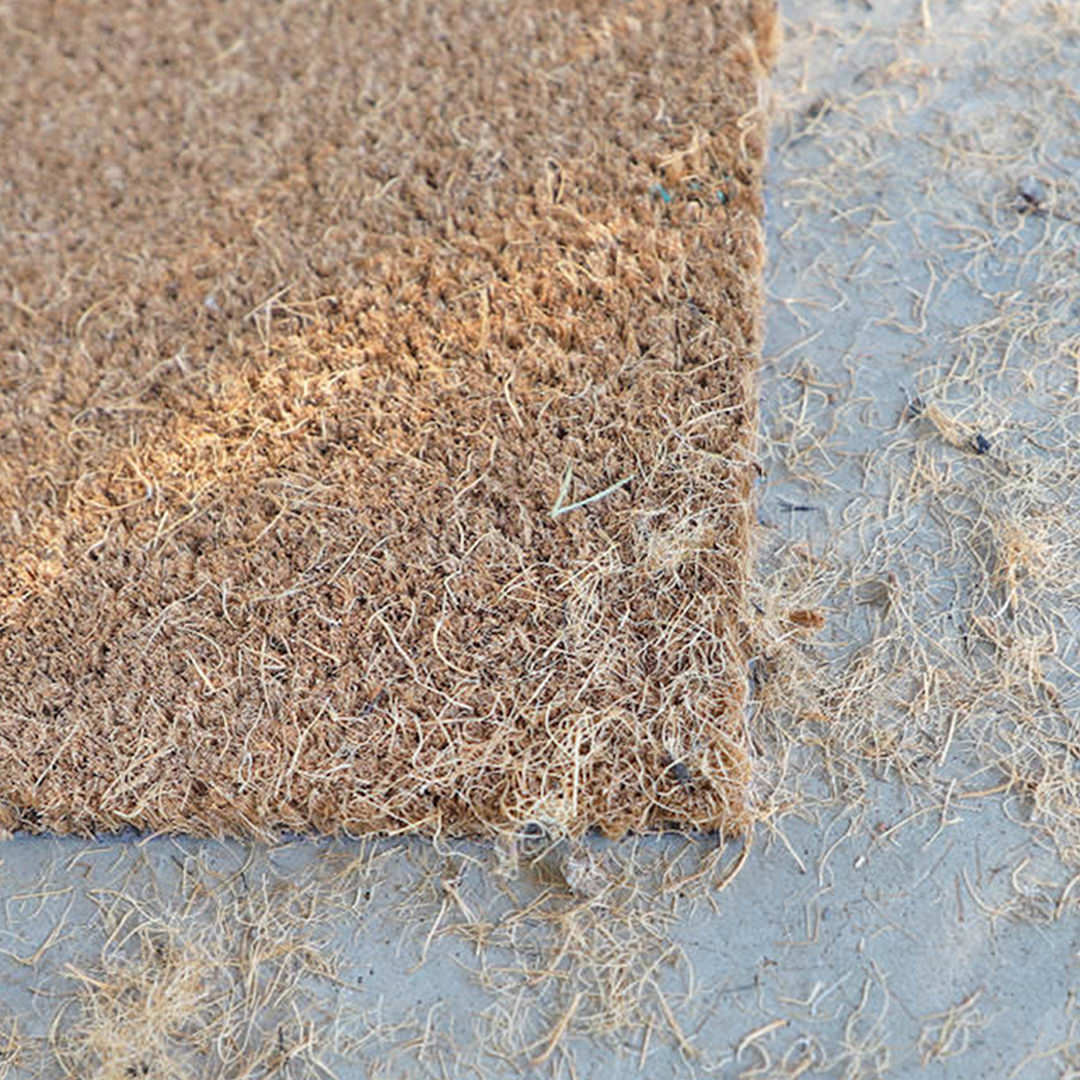 Close up image of a coco doormat that has shed it's fibers all around.